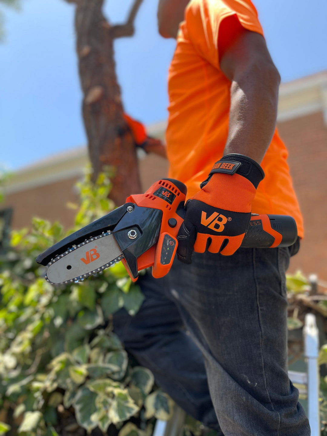 Trabajador con guante van Beek utiliza minisierra eléctrica vBSE4 van Beek naranja para cortes precisos en madera. Ideal para poda, carpintería y bricolaje.