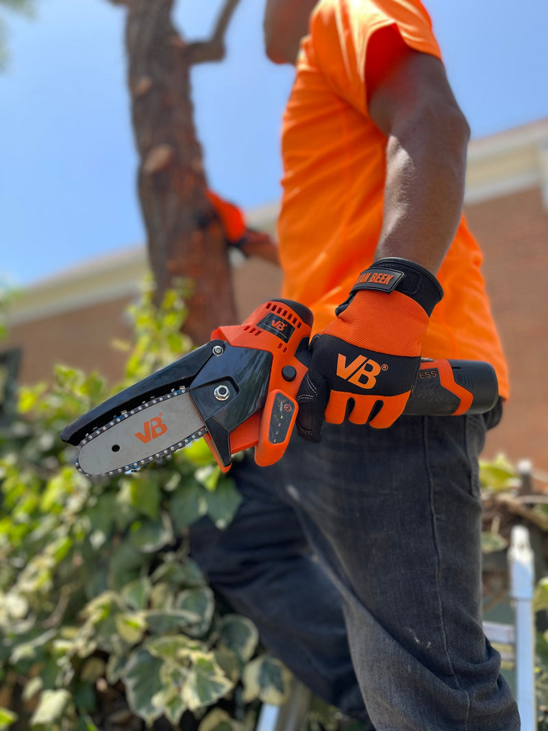 Trabajador con guante van Beek utiliza minisierra eléctrica vBSE4 van Beek naranja para cortes precisos en madera. Ideal para poda, carpintería y bricolaje.